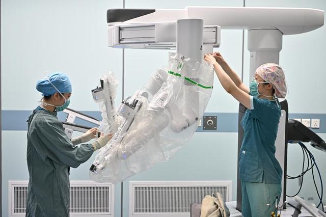 北京协和医院手术室护士王辉（右）和护士崔新冉为达芬奇机器人臂安装无菌罩。 新华社记者 李鑫 摄